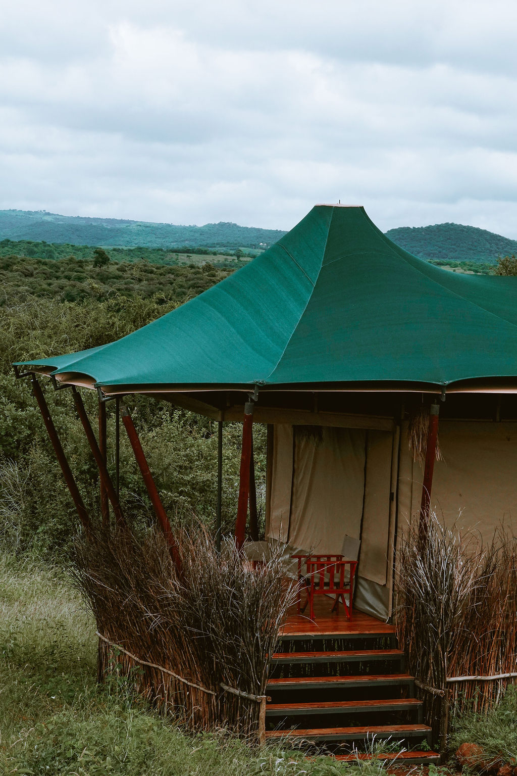 A red chair on a tent veranda overlooking the Rift Valley at sunrise