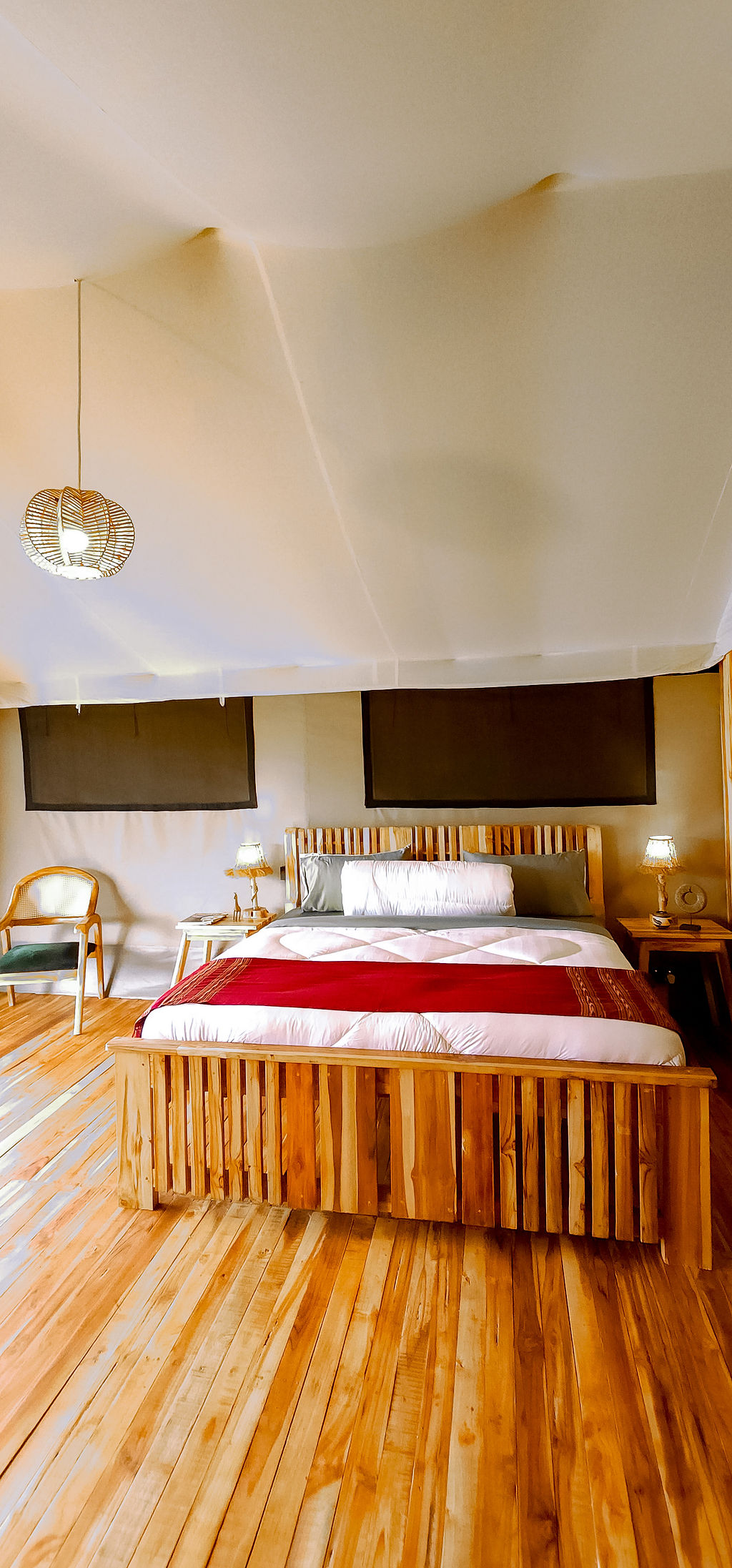Inside a tent at first light — bed, canvas ceiling, soft side-lantern
